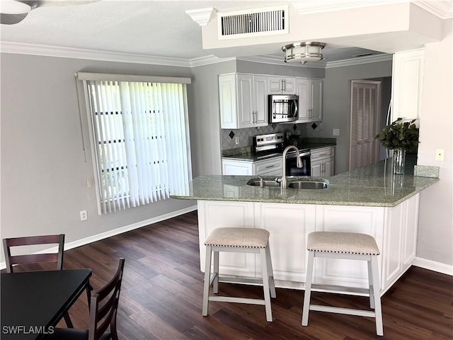 kitchen with kitchen peninsula, light stone counters, white cabinets, and stainless steel appliances