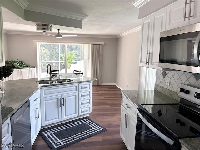 kitchen featuring ceiling fan, sink, stainless steel appliances, dark stone countertops, and white cabinets