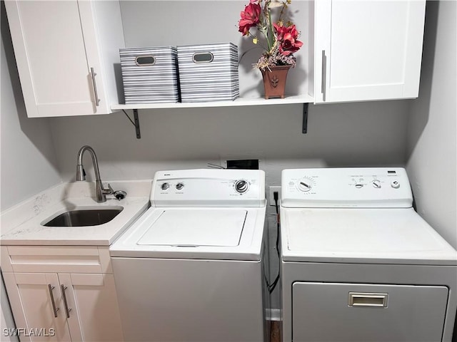 laundry area featuring washer and dryer, cabinets, and sink