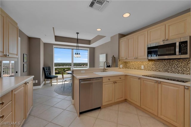 kitchen with sink, decorative light fixtures, appliances with stainless steel finishes, kitchen peninsula, and a raised ceiling