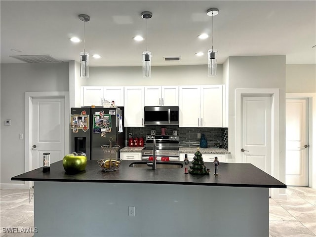 kitchen featuring a kitchen island with sink, sink, appliances with stainless steel finishes, decorative light fixtures, and white cabinetry