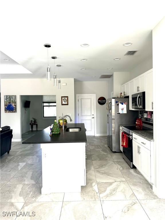 kitchen with white cabinetry, sink, stainless steel appliances, an island with sink, and pendant lighting