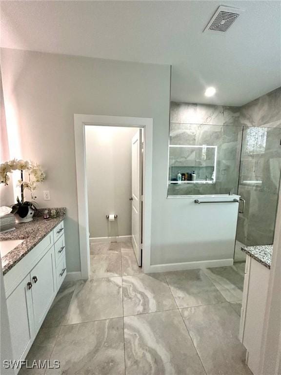 bathroom featuring a shower with door and vanity