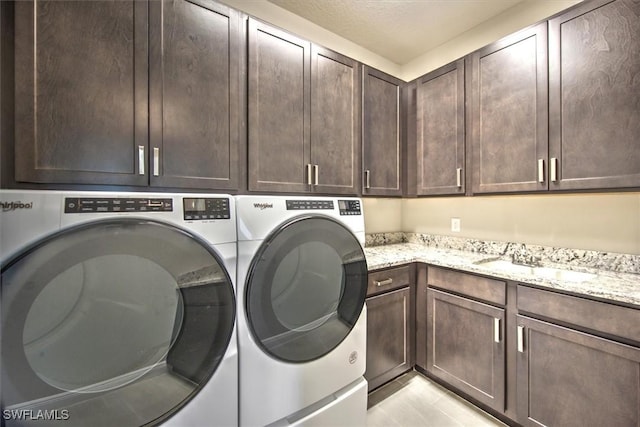 laundry room featuring cabinets, light tile patterned floors, separate washer and dryer, and sink