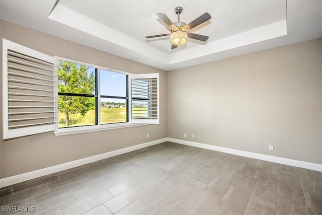 unfurnished room featuring ceiling fan and a raised ceiling