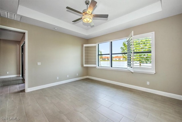 unfurnished room with ceiling fan and a raised ceiling