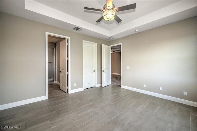 unfurnished bedroom with ceiling fan and a tray ceiling