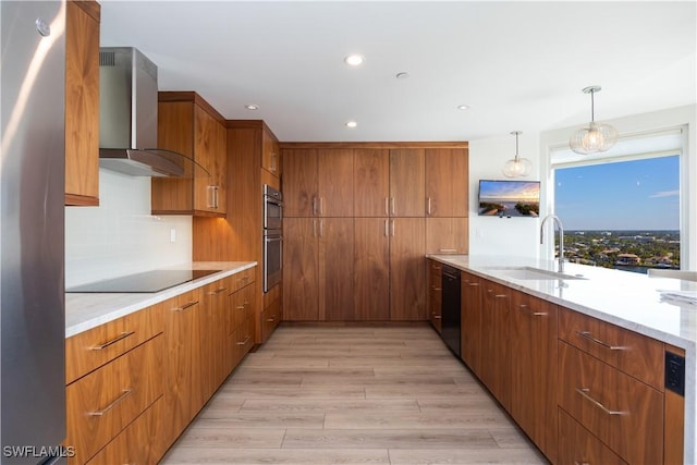 kitchen featuring sink, hanging light fixtures, black appliances, decorative backsplash, and wall chimney exhaust hood