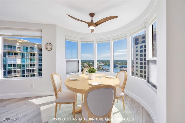 dining room with light wood-type flooring, ceiling fan, and a water view