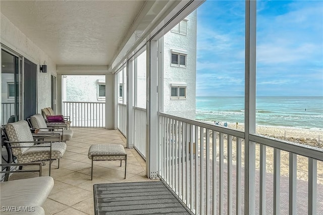 balcony featuring a beach view and a water view