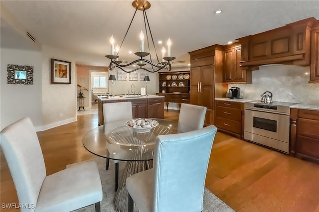 dining room featuring a chandelier, sink, and light hardwood / wood-style floors