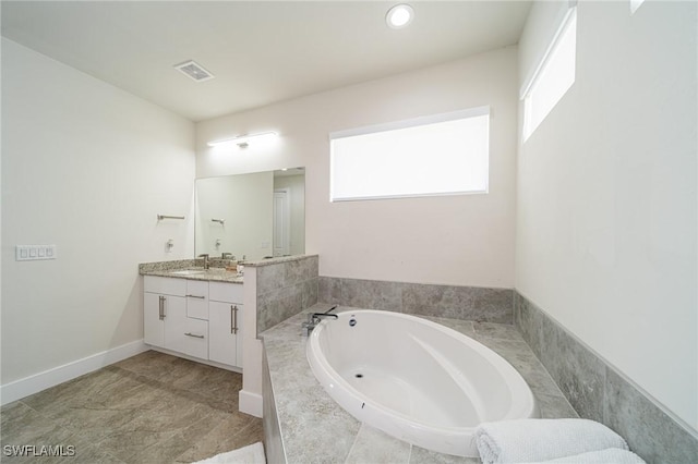 bathroom featuring vanity and tiled tub