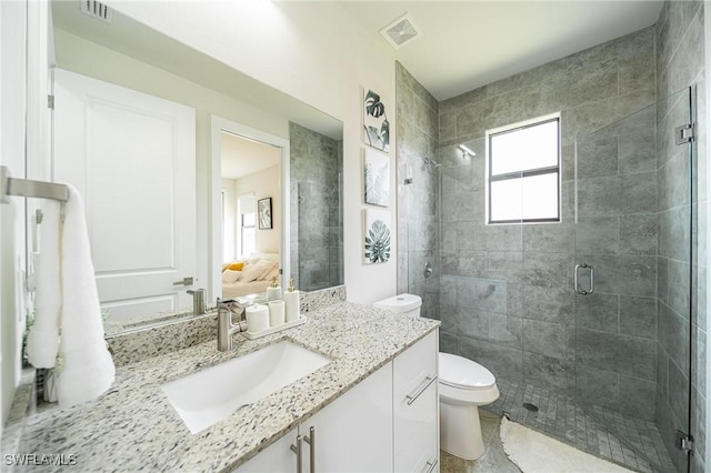 bathroom featuring vanity, a shower with shower door, and toilet