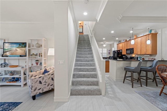 staircase with ceiling fan and crown molding