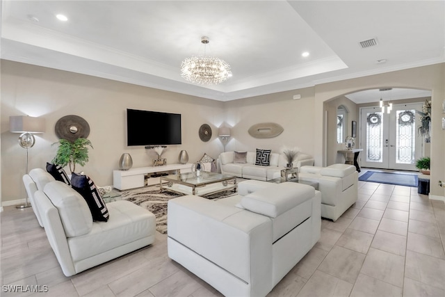 tiled living room featuring crown molding, a notable chandelier, a tray ceiling, and french doors