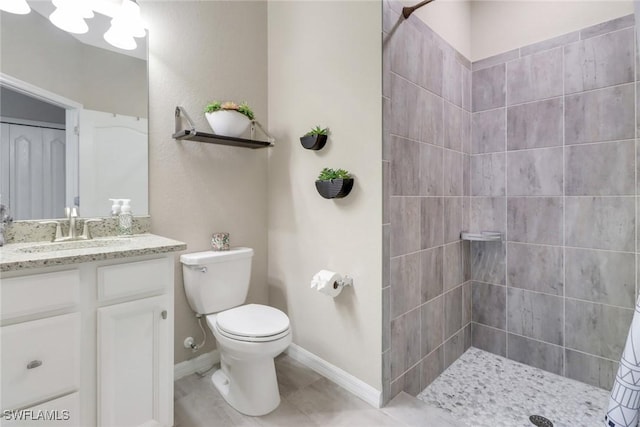 bathroom featuring tile patterned floors, toilet, vanity, and a tile shower