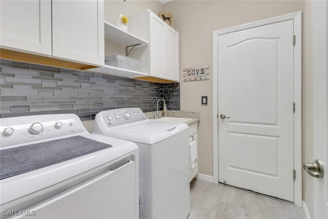 laundry area featuring sink, separate washer and dryer, and cabinets