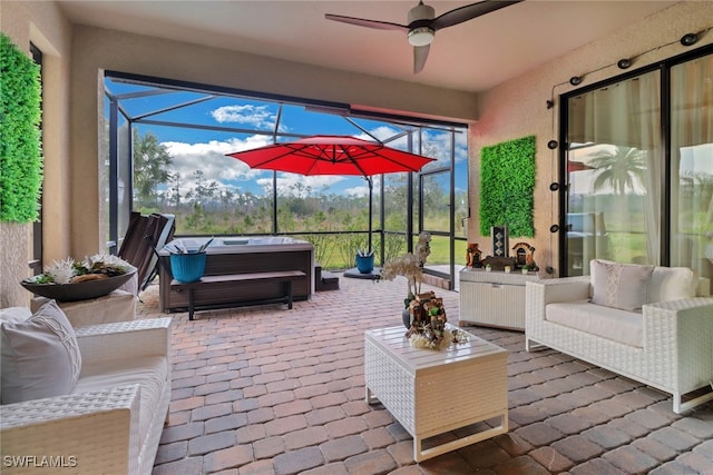 view of patio featuring ceiling fan, a lanai, an outdoor hangout area, and a hot tub