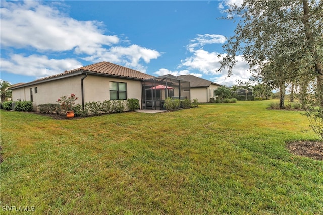 rear view of property featuring a lanai and a lawn