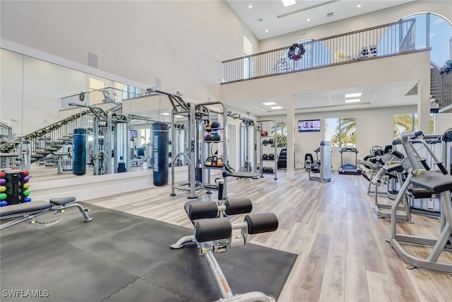 gym with hardwood / wood-style floors and a towering ceiling