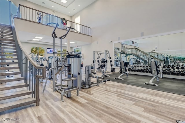 gym with light hardwood / wood-style flooring and a high ceiling