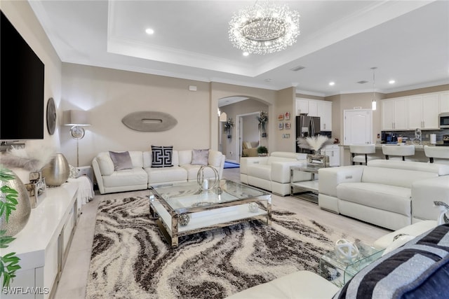 living room featuring a notable chandelier, crown molding, sink, and a tray ceiling