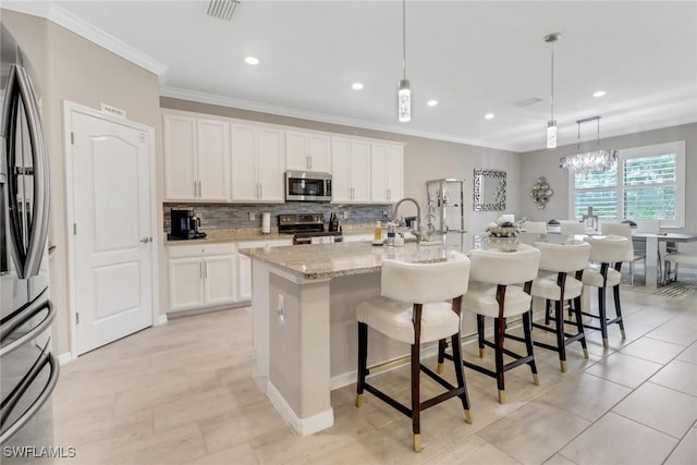 kitchen featuring a center island with sink, white cabinets, hanging light fixtures, and appliances with stainless steel finishes