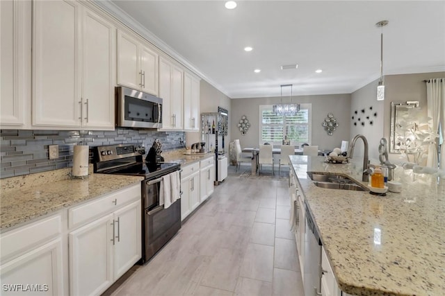 kitchen with appliances with stainless steel finishes, sink, decorative light fixtures, white cabinets, and light stone counters