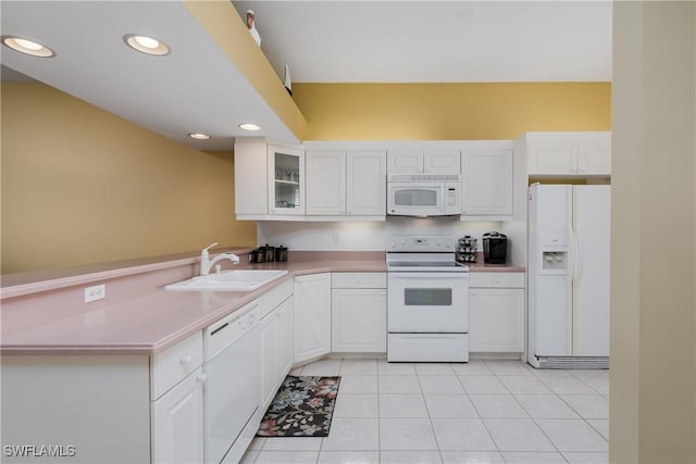 kitchen with kitchen peninsula, white appliances, sink, light tile patterned floors, and white cabinetry