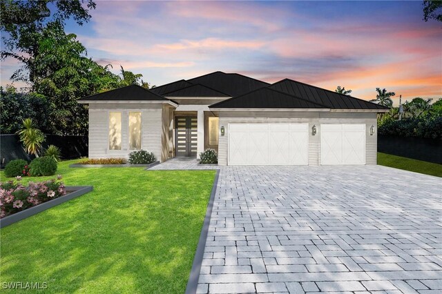 view of front of property featuring a garage, a lawn, and french doors