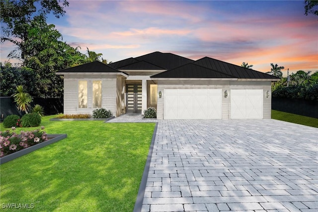 view of front of house with a garage, a yard, and french doors