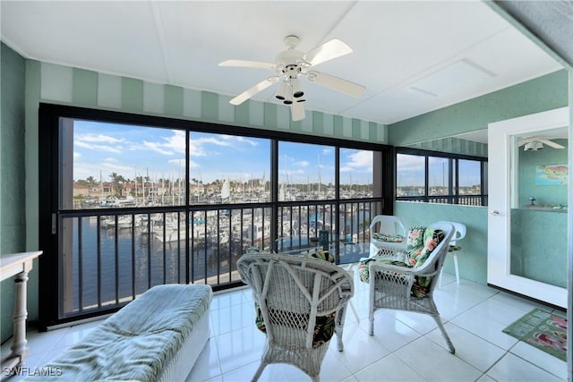 sunroom featuring ceiling fan and a water view