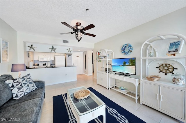 living room with light tile patterned floors, a textured ceiling, and ceiling fan