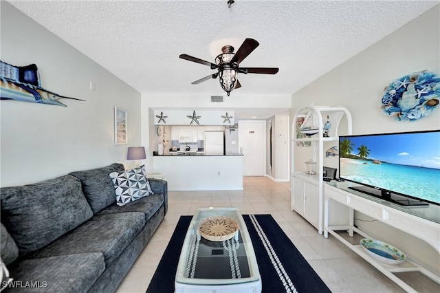 living room featuring ceiling fan, light tile patterned flooring, and a textured ceiling