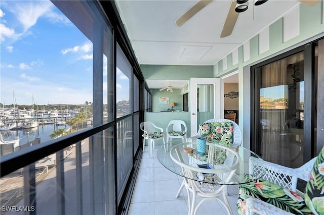 sunroom featuring ceiling fan and a water view