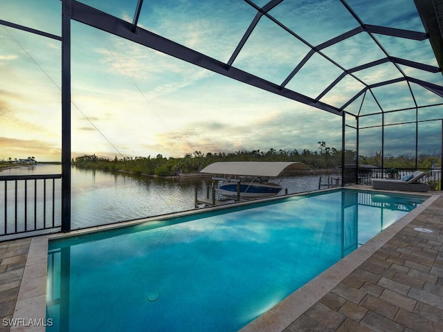 pool at dusk featuring glass enclosure, a water view, and a boat dock