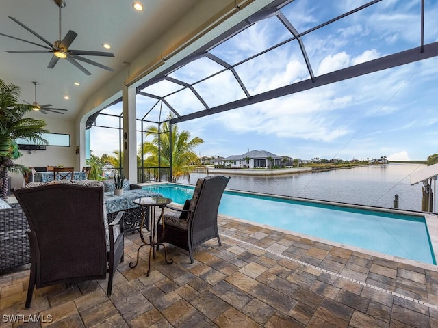 view of swimming pool featuring glass enclosure, ceiling fan, a water view, and a patio