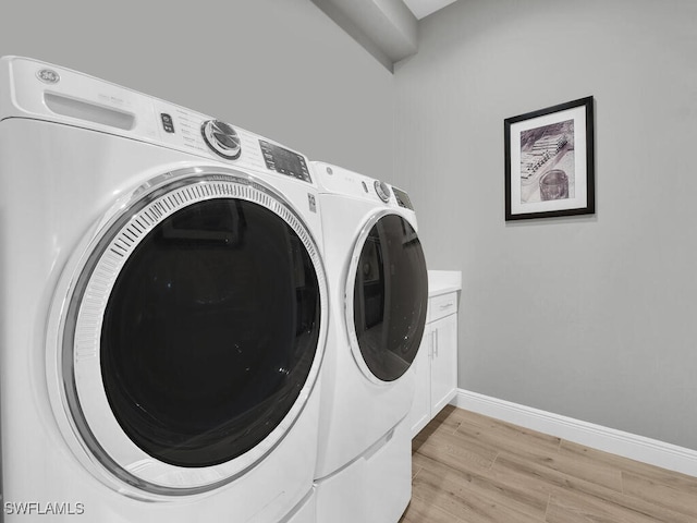 washroom with washer and dryer, light hardwood / wood-style floors, and cabinets