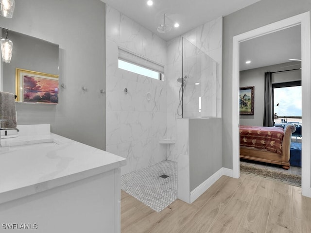 bathroom with hardwood / wood-style flooring, vanity, and tiled shower