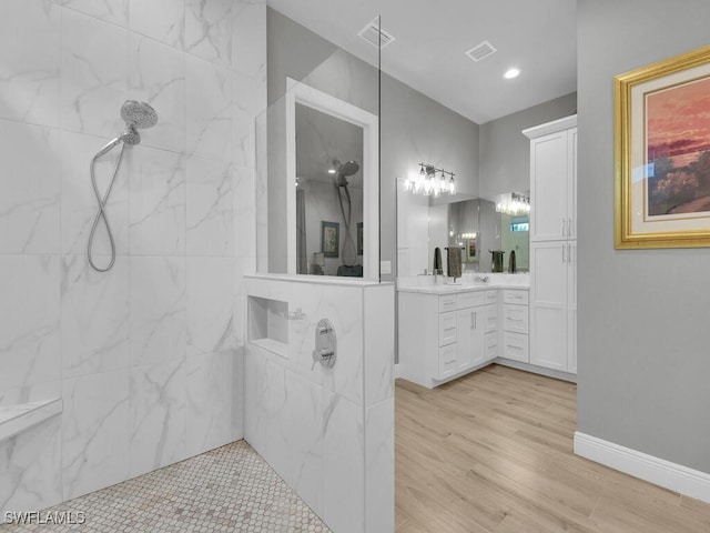 bathroom with hardwood / wood-style floors, vanity, and a tile shower