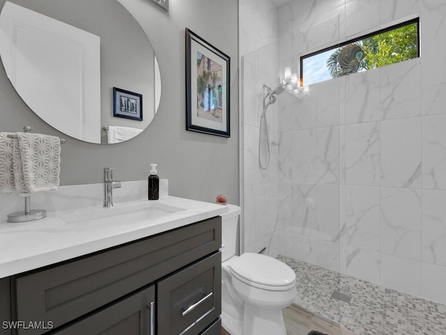 bathroom with a tile shower, vanity, and toilet