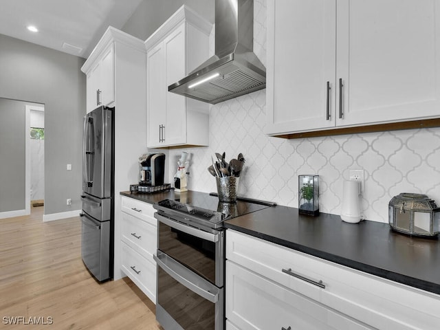 kitchen with wall chimney range hood, appliances with stainless steel finishes, tasteful backsplash, light hardwood / wood-style floors, and white cabinetry