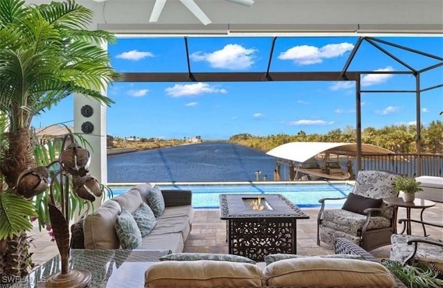 view of pool with ceiling fan, a water view, an outdoor living space with a fire pit, and a patio