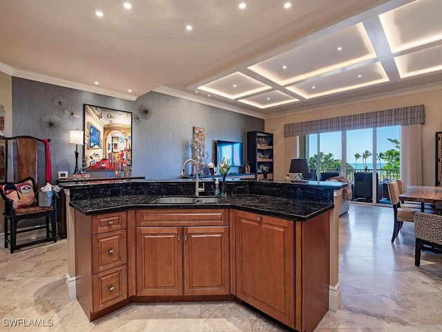 kitchen featuring dark stone counters, a center island with sink, coffered ceiling, and sink