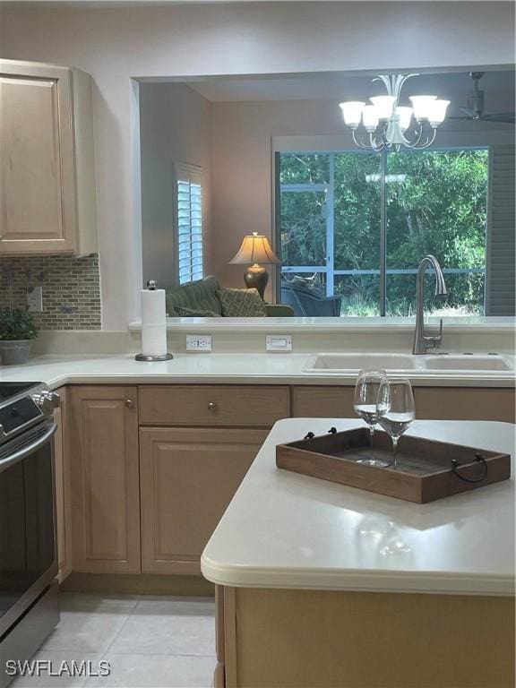 kitchen with sink, an inviting chandelier, electric stove, decorative backsplash, and light tile patterned flooring