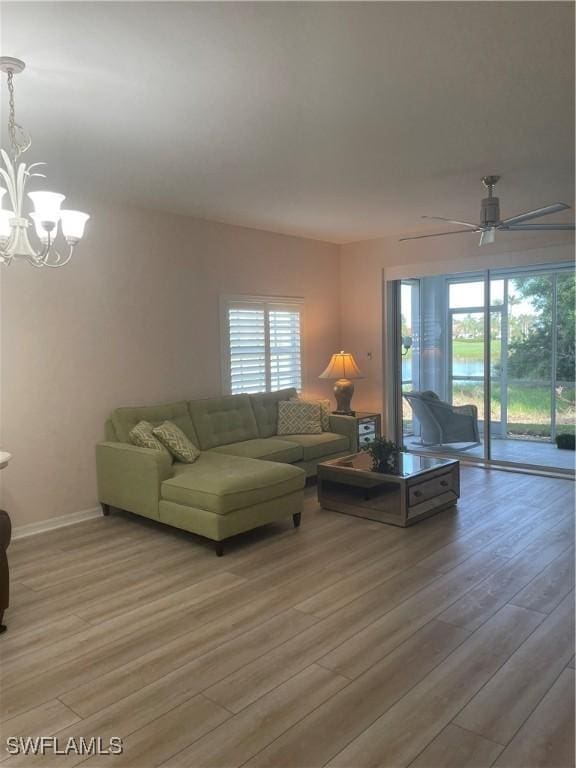 living room featuring ceiling fan with notable chandelier and hardwood / wood-style flooring