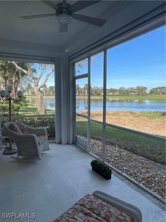 sunroom / solarium with a water view and ceiling fan