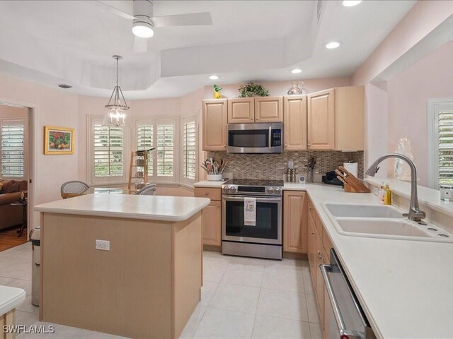 kitchen with hanging light fixtures, sink, light brown cabinetry, appliances with stainless steel finishes, and a tray ceiling