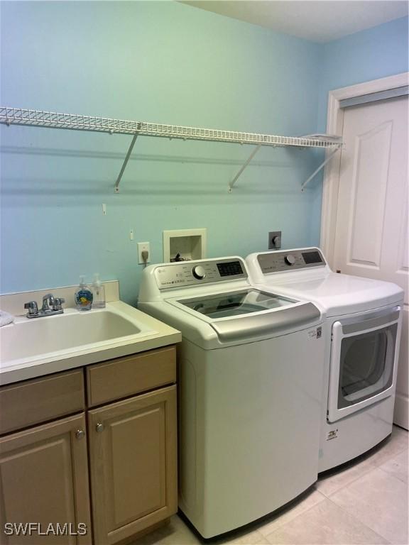 laundry area with cabinets, separate washer and dryer, sink, and light tile patterned floors