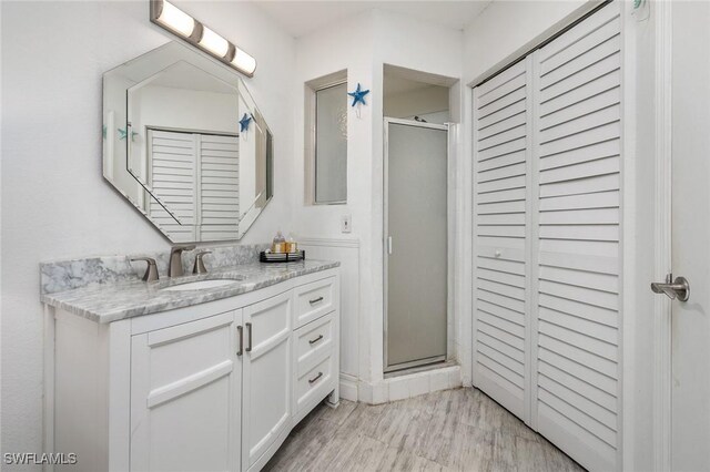 bathroom with hardwood / wood-style flooring, an enclosed shower, and vanity